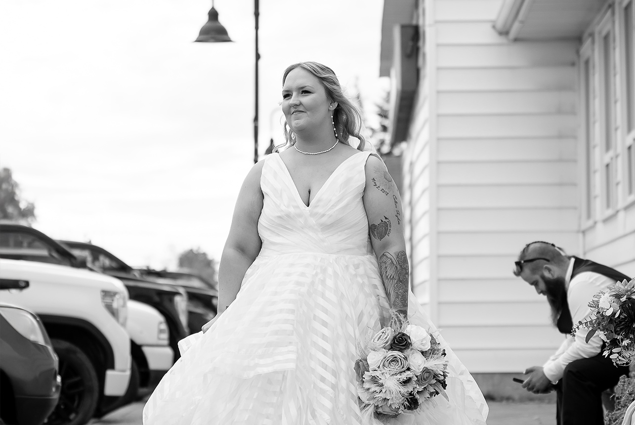 Black-and-white photo of the bride walking alone down the street in Redwater, looking forward with determination