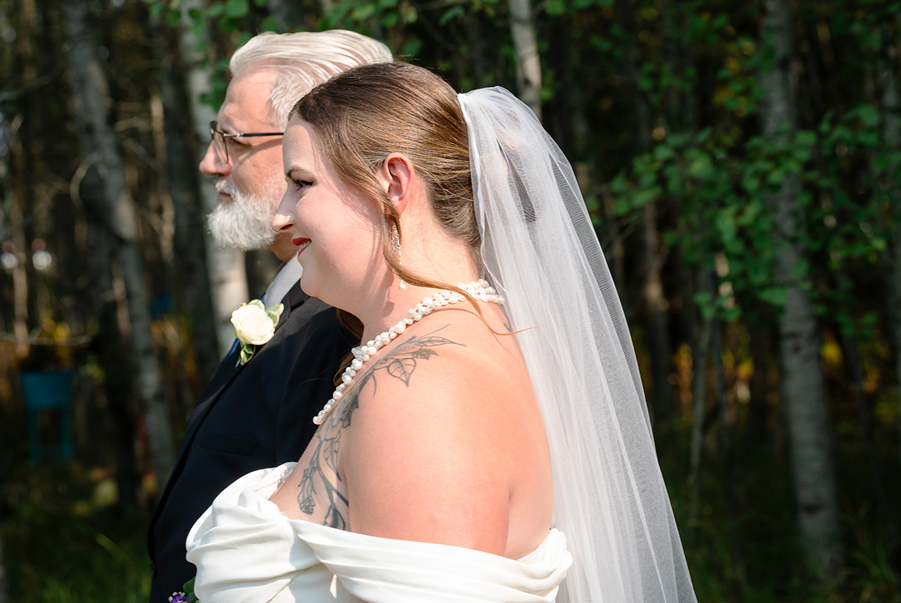 Bride and father share a heartfelt moment, walking together through a sunlit forest path before the wedding ceremony
