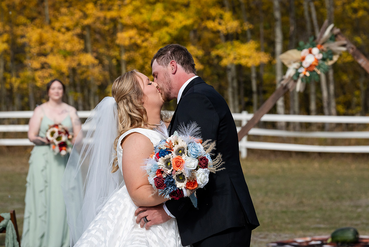 Bride and groom walk up the aisle, showing off their wedding rings as the wedding party celebrates with them at Finnegan Farms