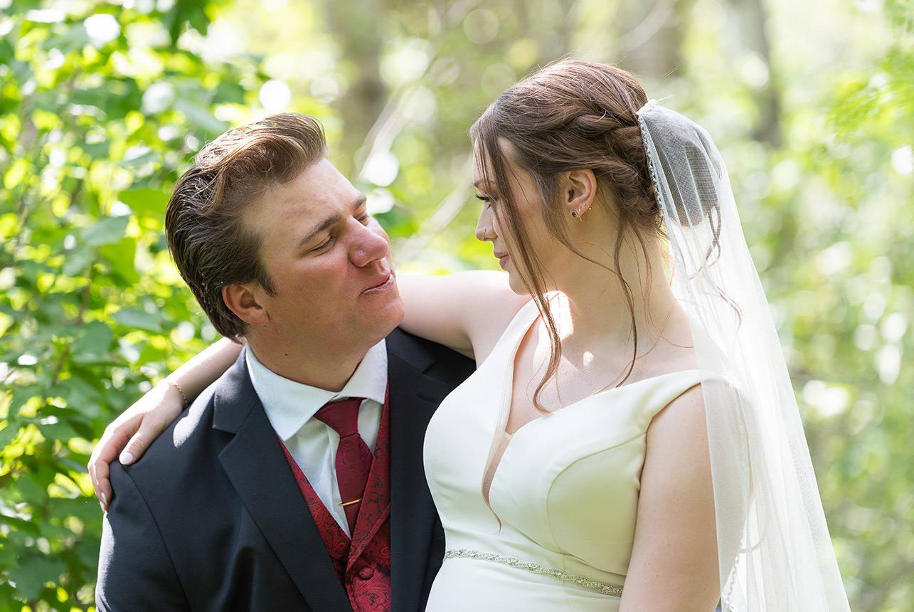 Bride and groom gazing at each other in forest setting