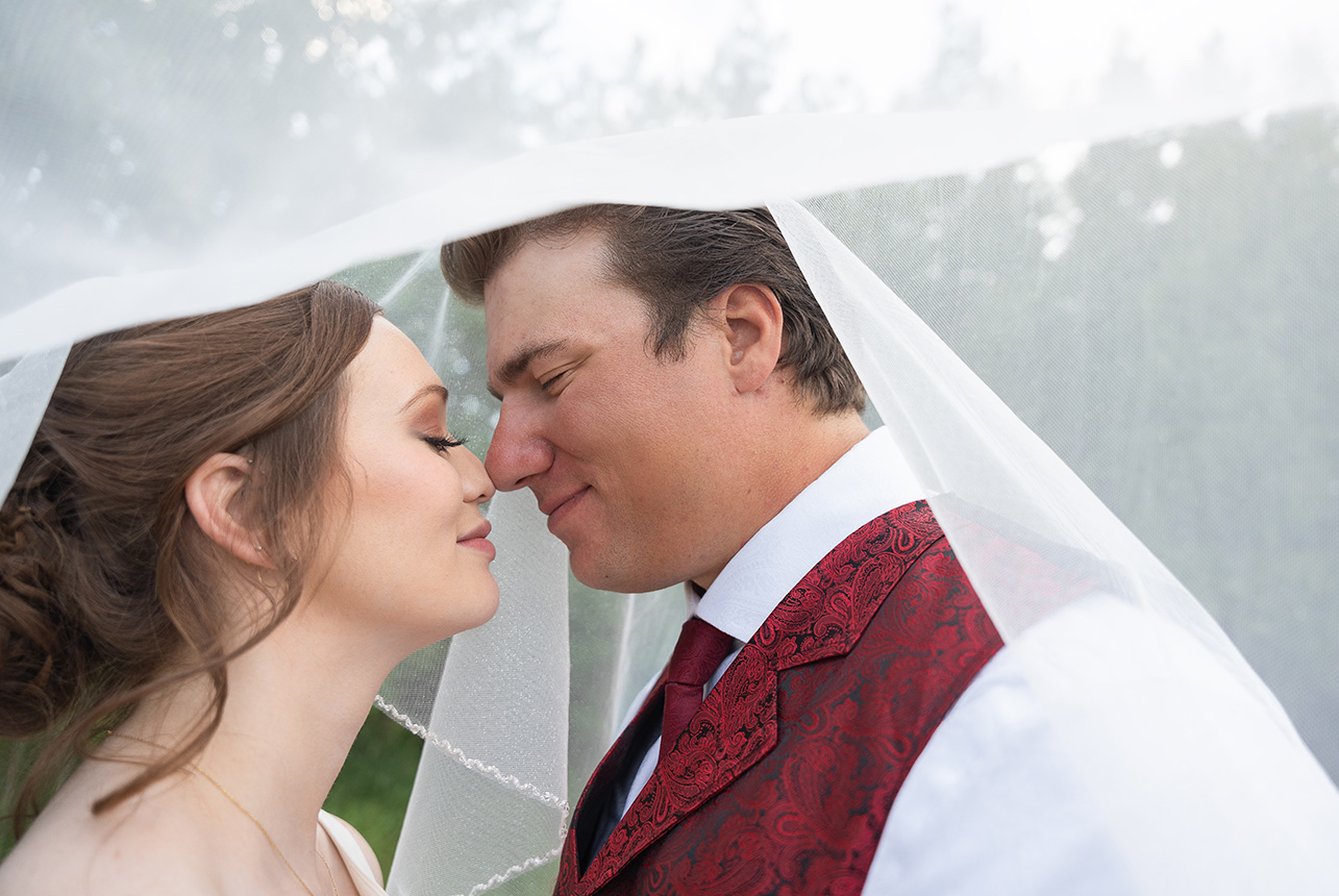 Bride and groom sharing intimate moment under wedding veil