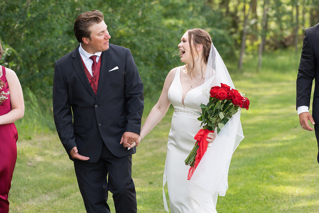 Bride and groom walking hand in hand with red rose bouquet