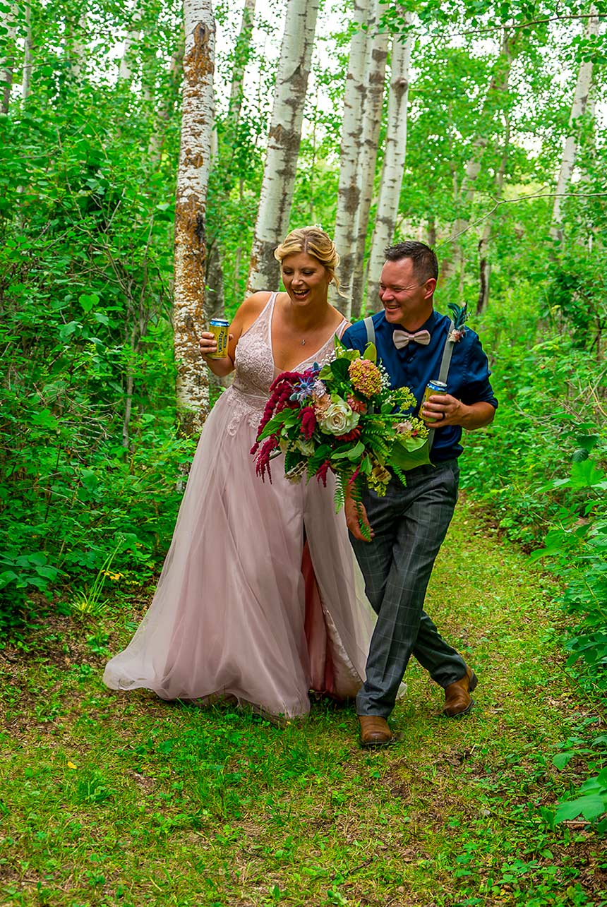 Bride and groom walking through a green forest trail, smiling and relaxed