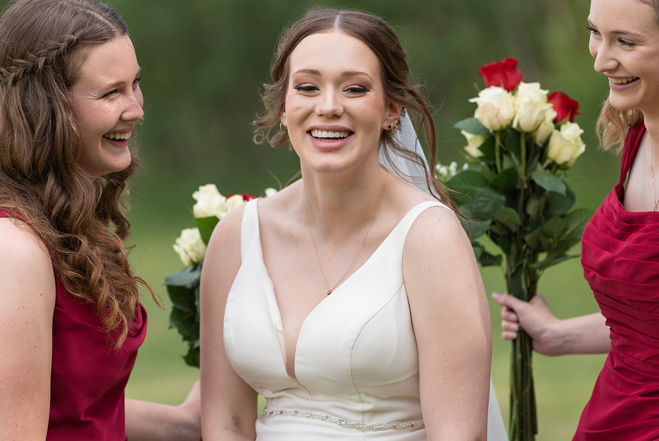 Bride laughing with bridesmaids holding roses