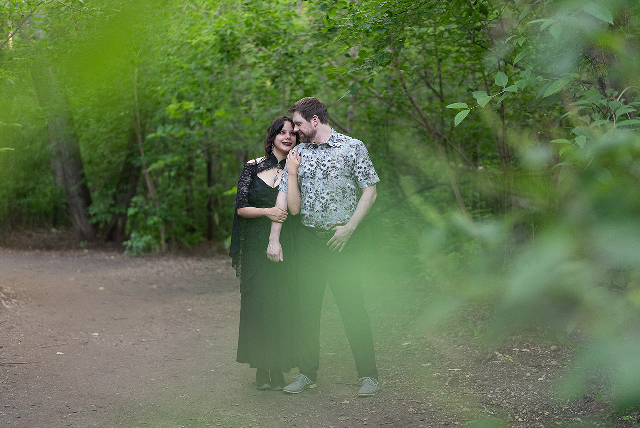 couple-embrace-through-forest-leaves-mill-creek-edmonton