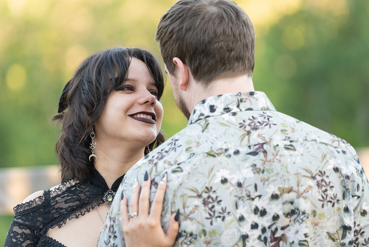 Emily gazes at Gary with a joyful smile, wearing a black lace dress
