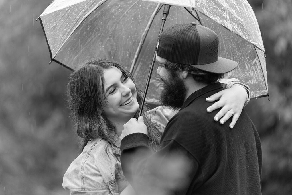 Brylie and Rylie share a laugh under an umbrella during their rainy Edmonton engagement session
