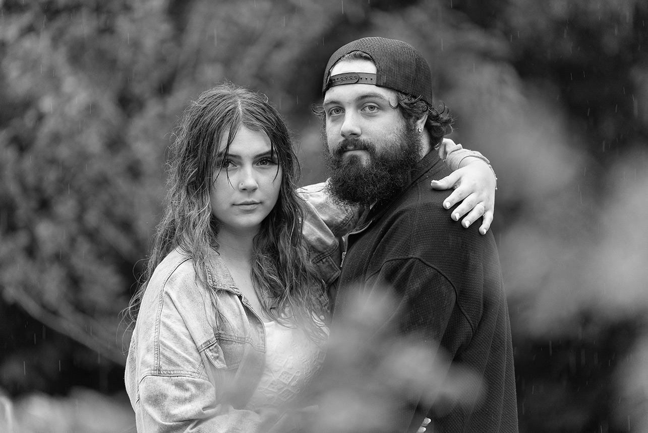 Close-up of couple with calm, serious expressions in the rain during Edmonton engagement session