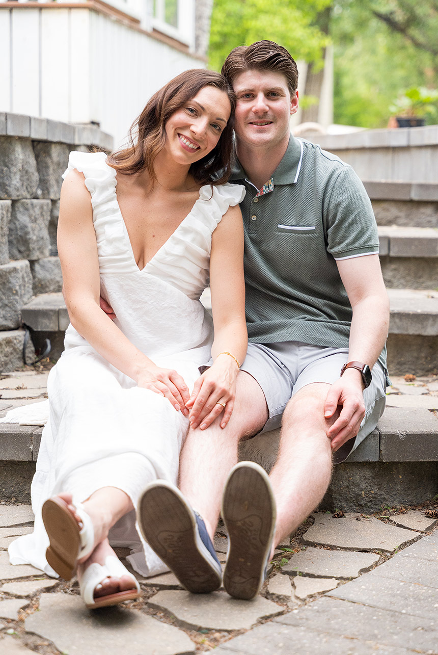 engaged couple sitting stone steps smiling Ava and Mathew sit close together on stone steps, smiling warmly during their outdoor engagement shoot