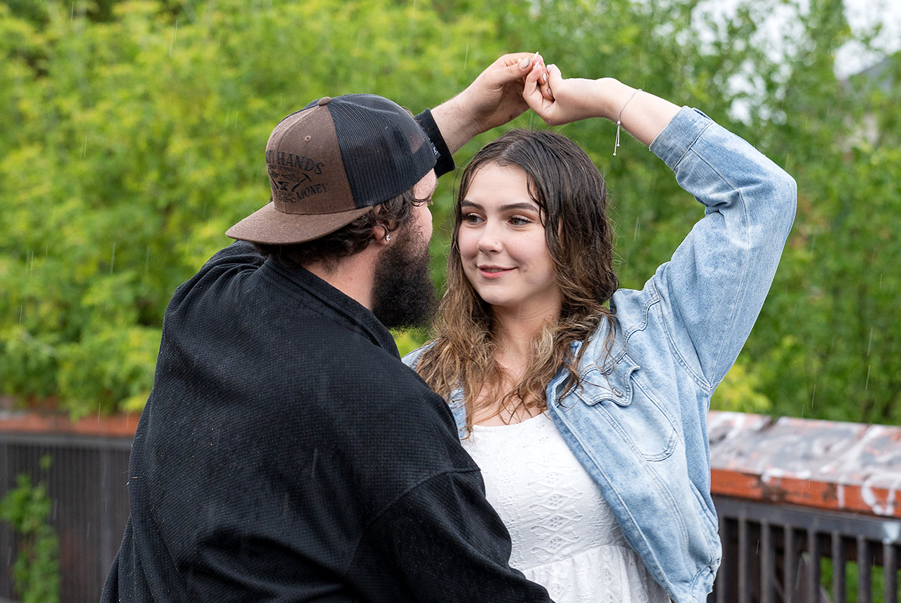 Couple dancing in the rain during engagement shoot on bridge