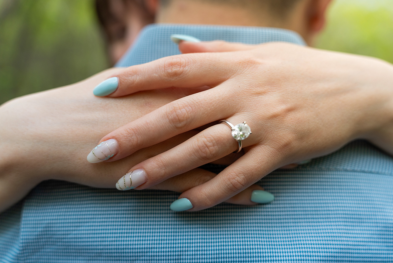 engagement ring close up spring embrace Close up of woman's hand with engagement ring resting on partner’s shoulder during spring session in Edmonton