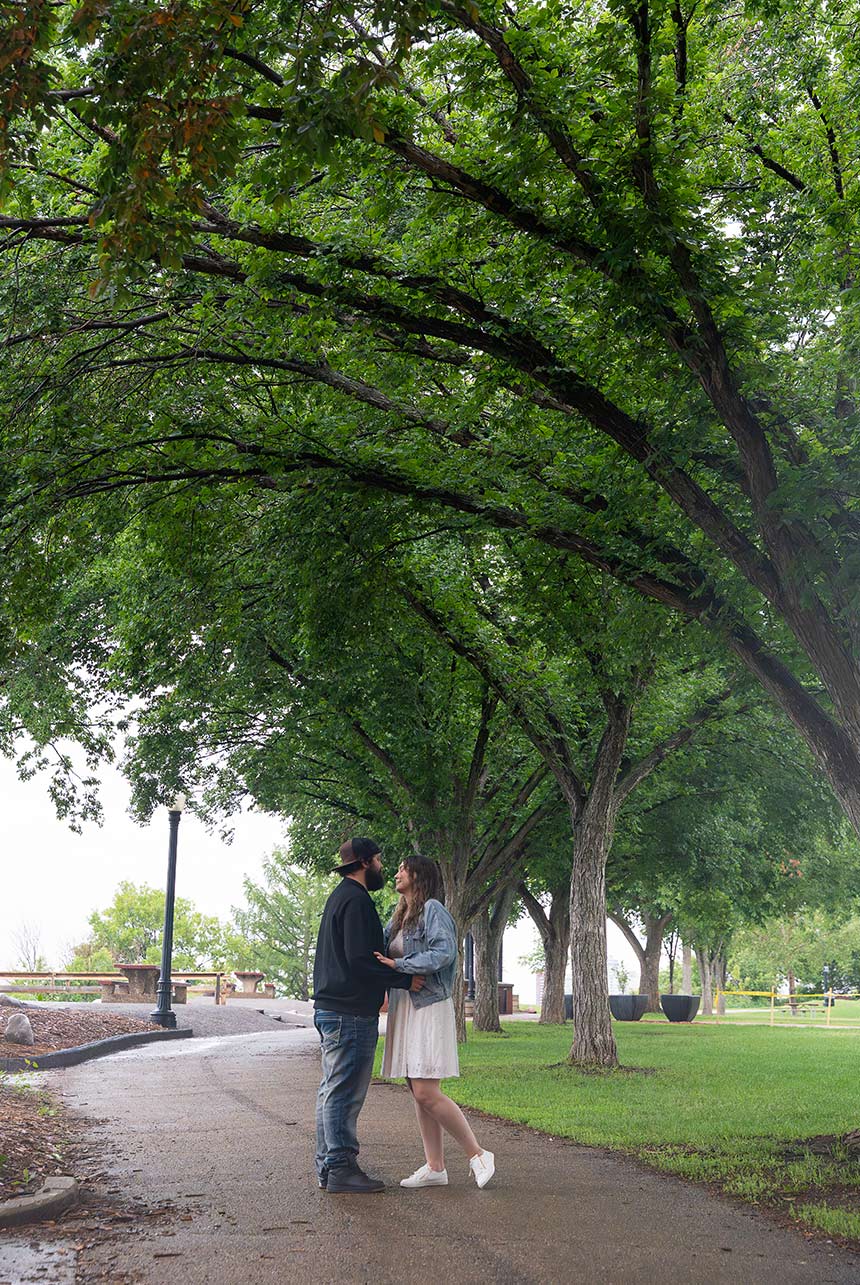 Couple shares a kiss under tall trees in Constable Ezio Faraone Park in Edmonton