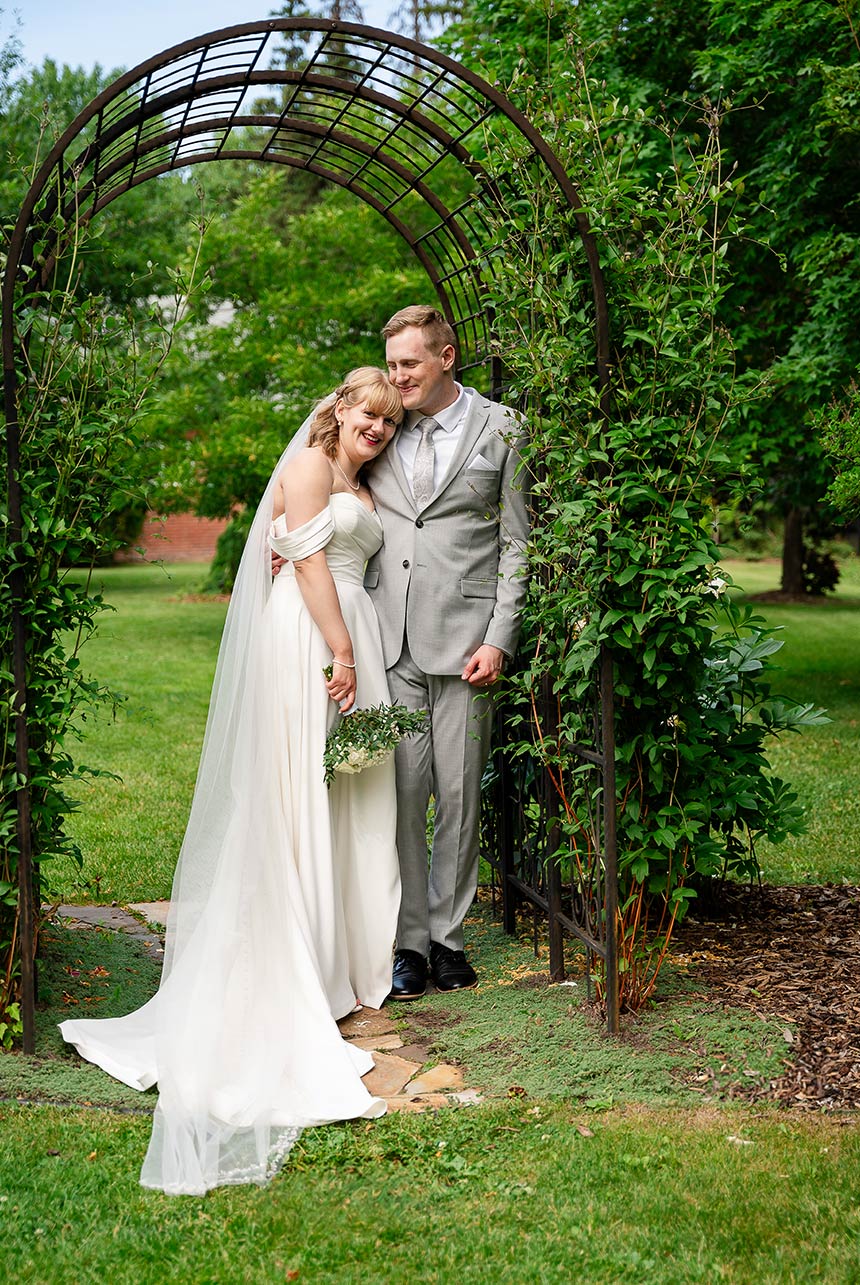 erin-eric-archway-snuggle Bride and groom cuddled under the vine-covered arch
