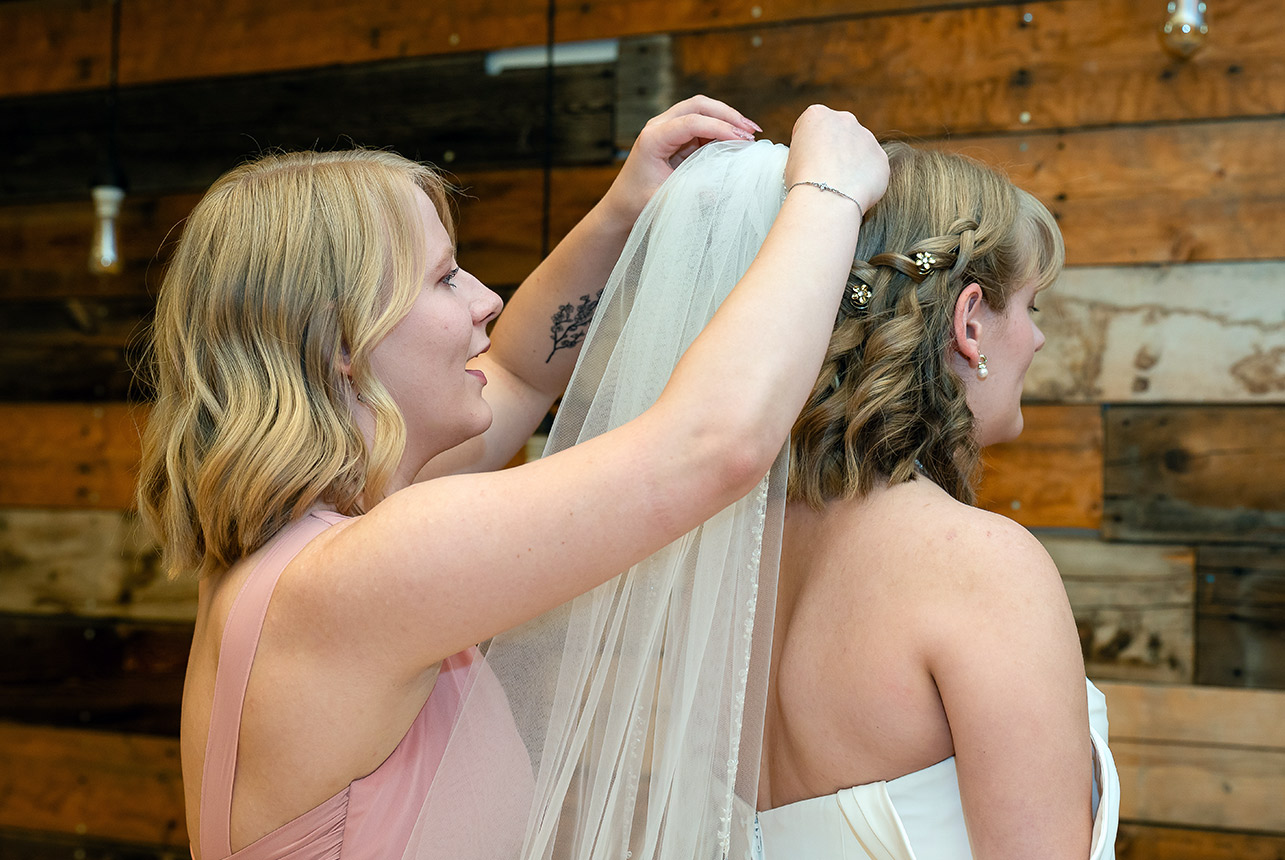 erin-eric-veil-moment-bridesmaid Bridesmaid adjusting bride’s veil before the ceremony