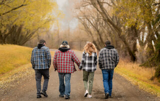 Family walking hand in hand down a country road in Alberta during autumn