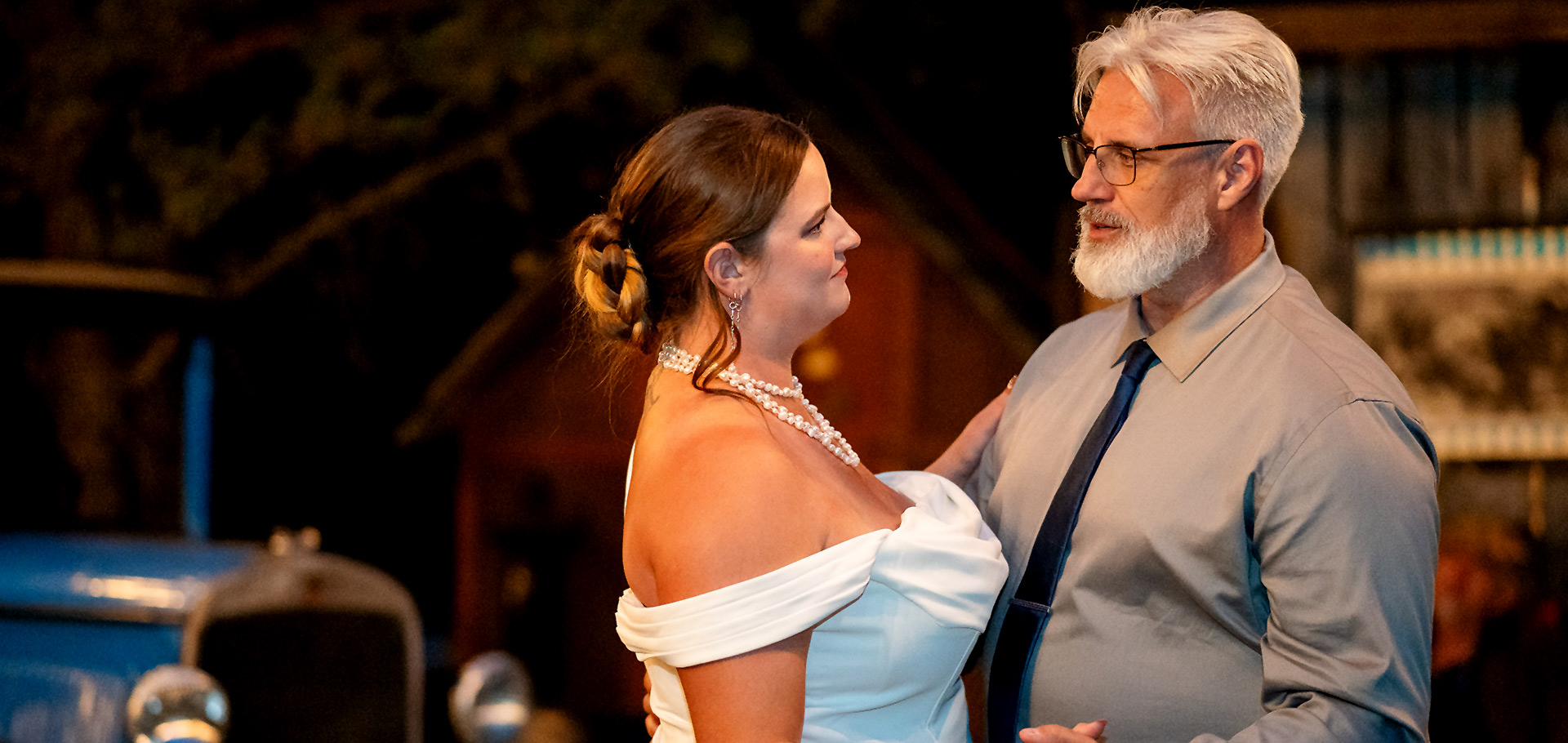 Bride and her father sharing a warm, glowing dance in front of a barn at a nighttime Edmonton wedding