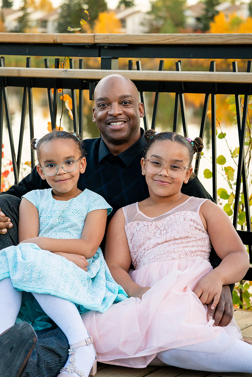 Father posing with his two daughters in elegant dresses during an autumn family session in Edmonton