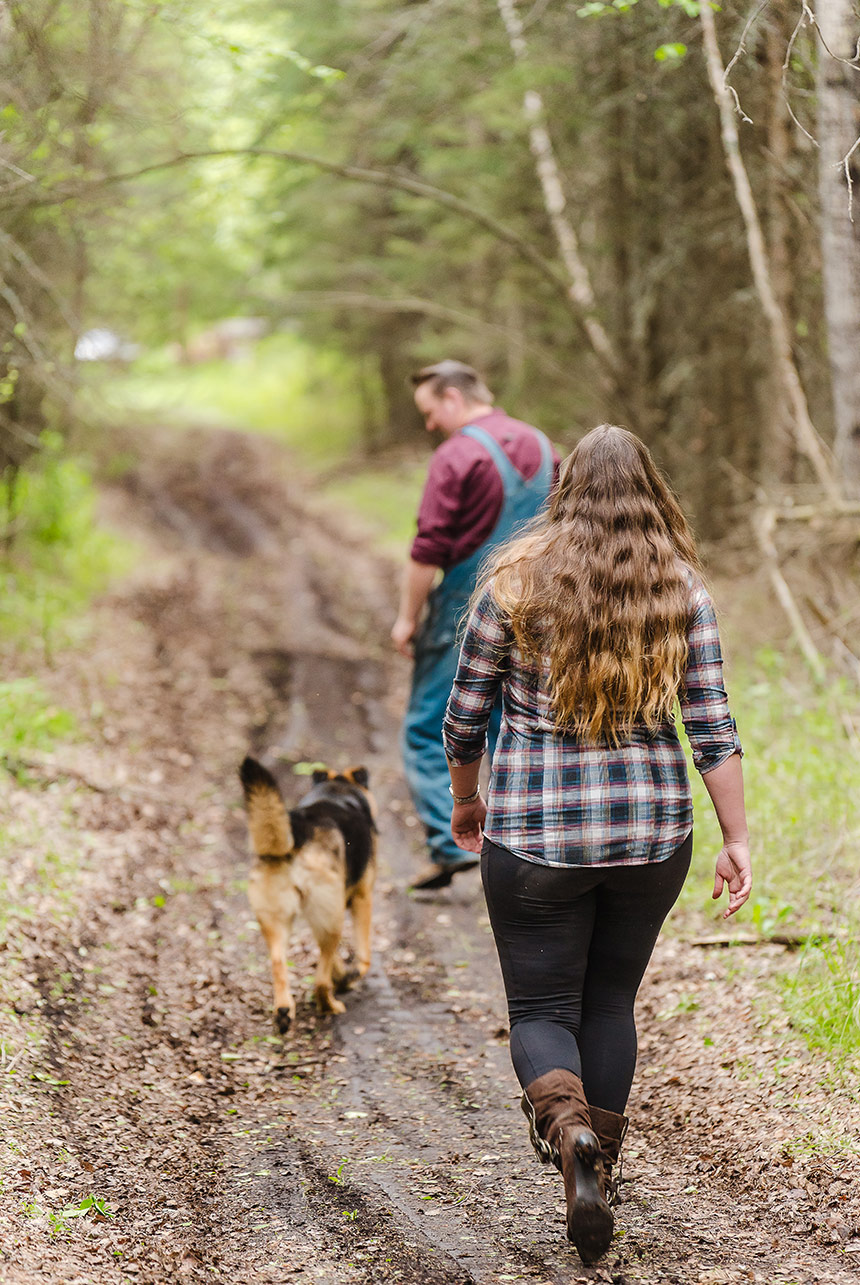 fiancée following her soon-to-be husband on a muddy forest trail with their dog