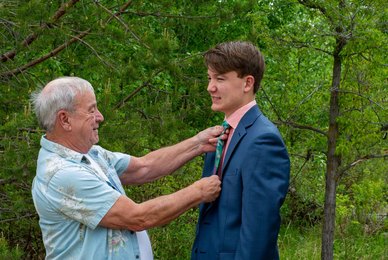 Grandpa fitting young man's tie