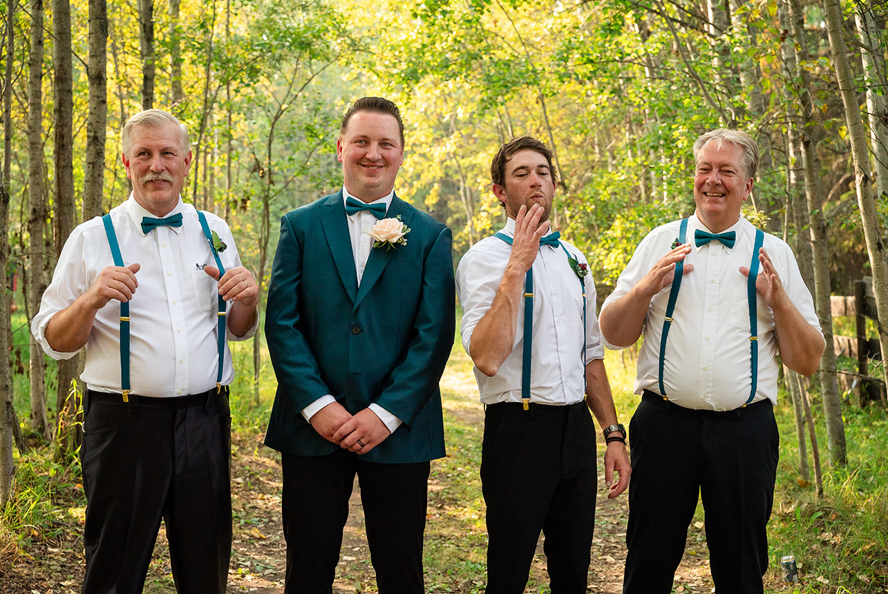 Groom and his groomsmen adjust their suspenders in a candid, relaxed moment before the wedding ceremony begins