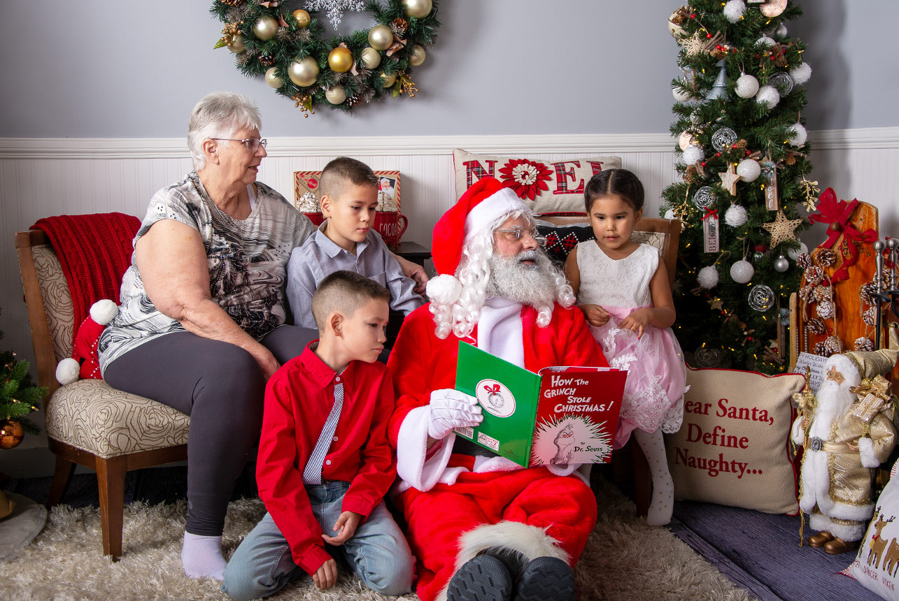 Holiday-Storytime-Family-Enraptured-as-Santa-Reads-Aloud-Encircled-by-Festive-Backdrop