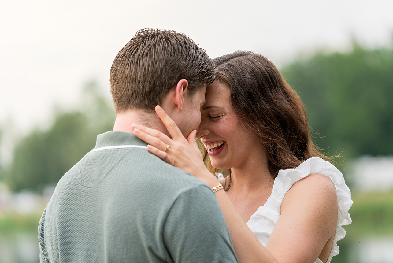 intimate laughter lakeside engagement moment Ava laughs with her forehead pressed to Mathew’s, hands gently resting on his shoulders near the lake