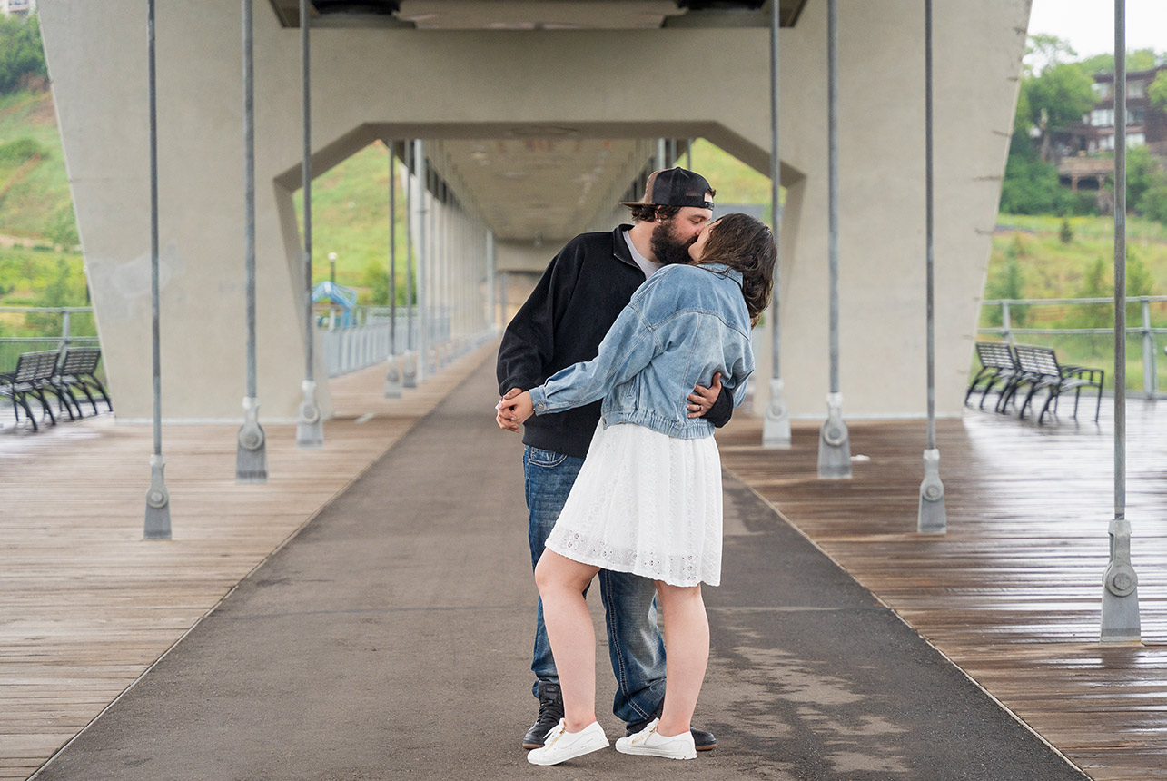 Couple kissing on Tawatinâ LRT Bridge during a summer rainstorm