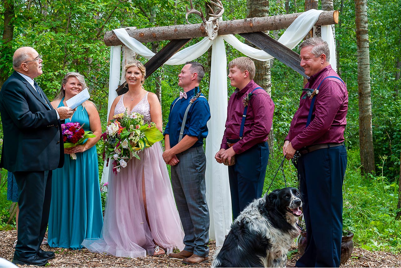 Bride and groom at altar with officiant and wedding party outdoors