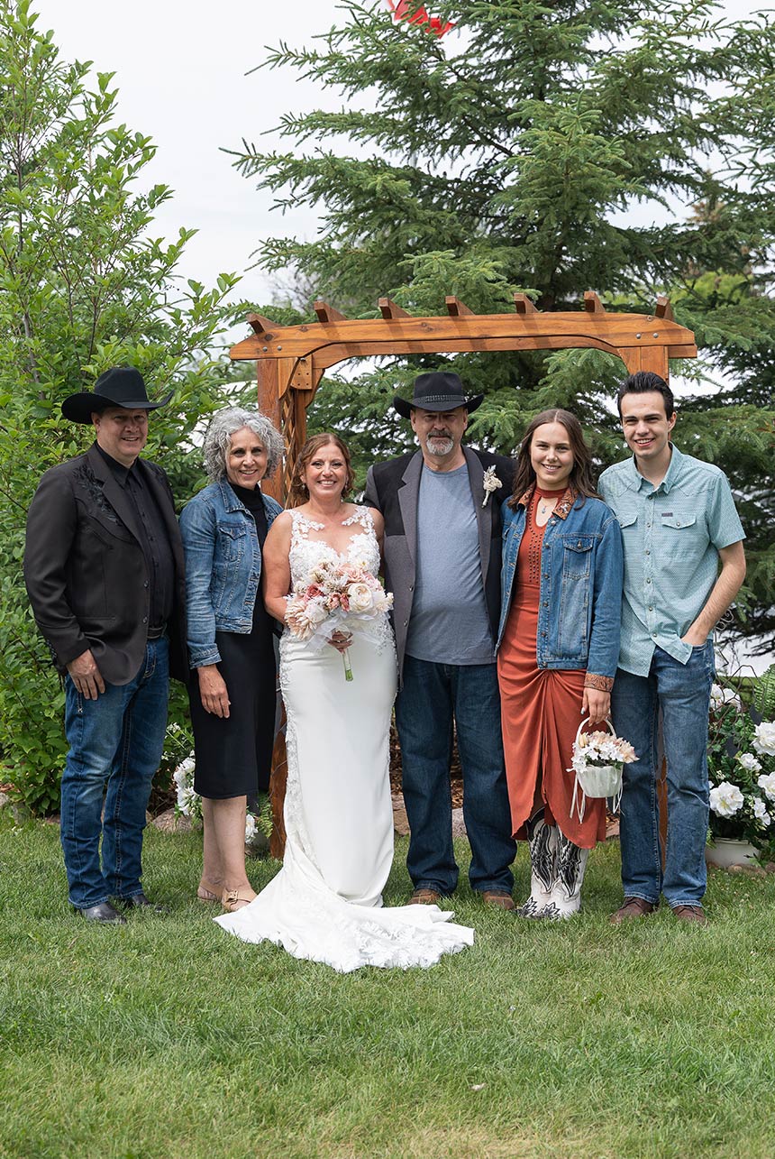 Wedding group photo under wooden arch at a Sherwood Park acreage