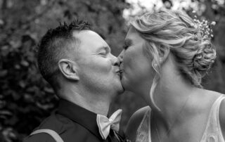 Close-up black and white image of bride and groom kissing