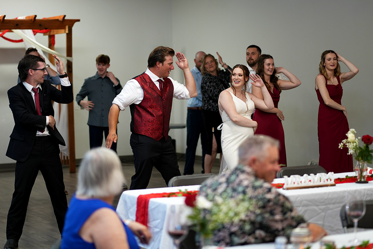 Bride and groom dancing with guests at indoor wedding reception