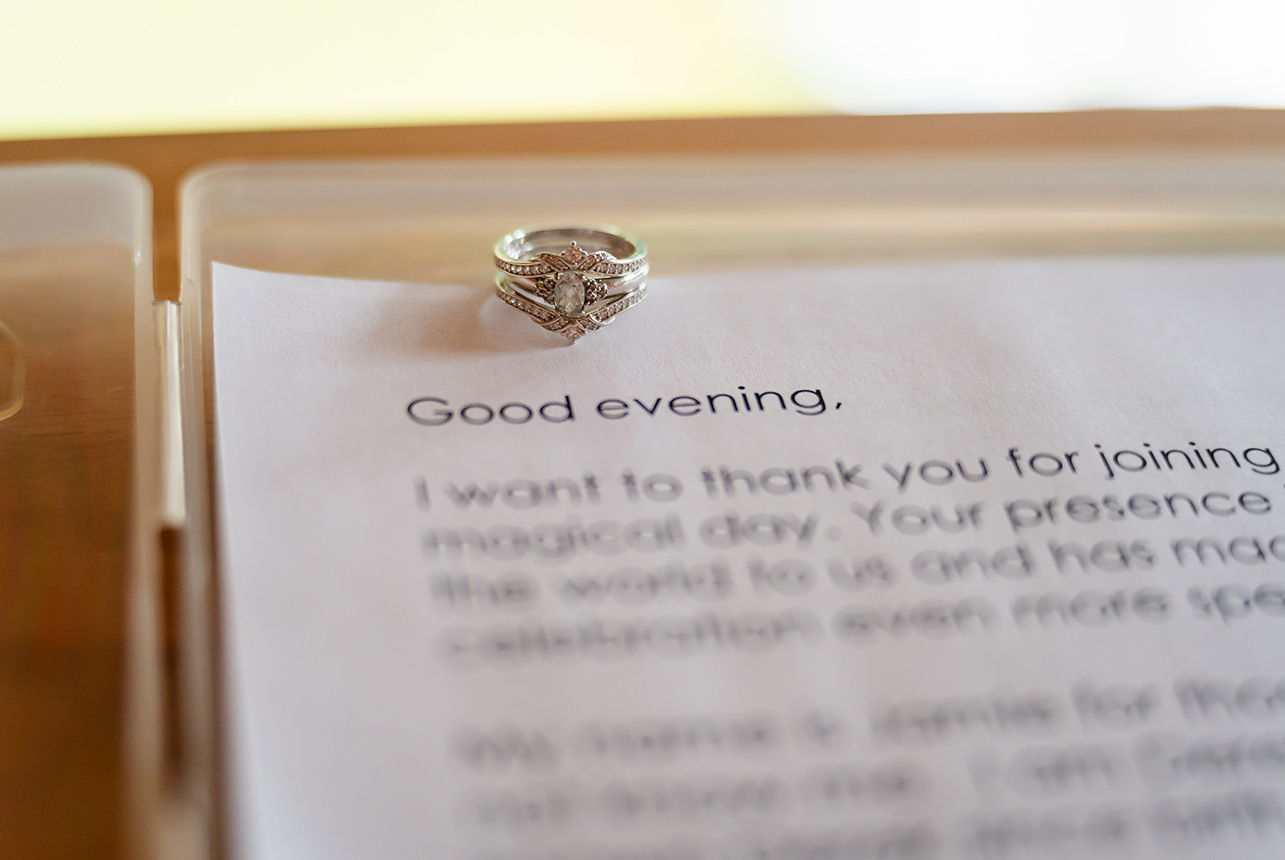 Close-up of the wedding ring resting on the commissioner’s script, with the words ‘Good evening’ softly visible in the background